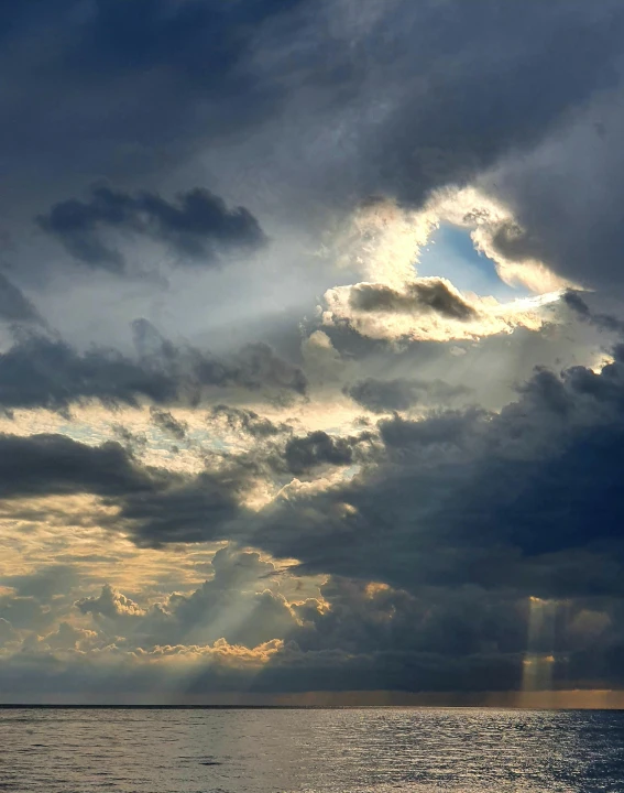 a large body of water under a cloudy sky, bursting with holy light, face in the clouds, trending photo