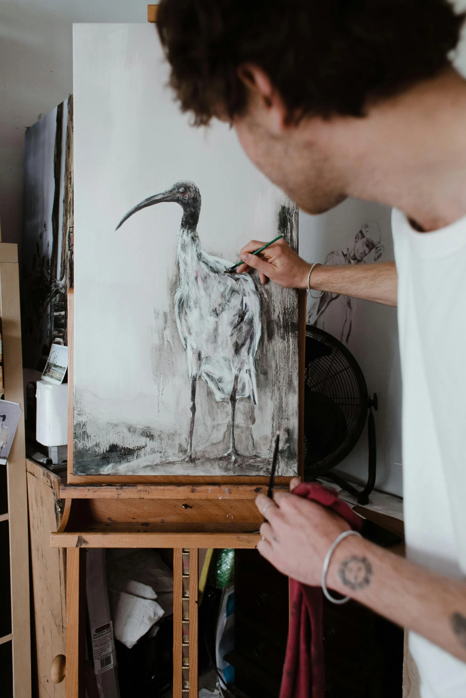 a man that is standing in front of a painting, a charcoal drawing, inspired by Fernand Verhaegen, trending on pexels, birds, holding a paintbrush, a painting of white silver, julian ope