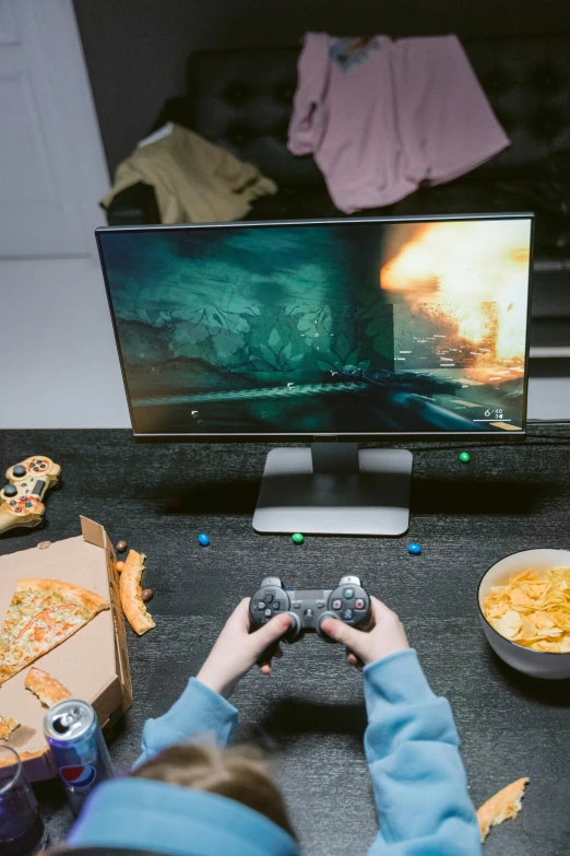 a person sitting in front of a tv playing a video game, pizza on a table, gaming pc, sci-fi themed, snacks