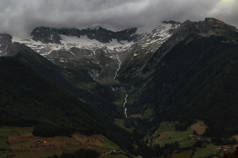 a view of a valley with mountains in the background, by Daniel Seghers, pexels contest winner, hurufiyya, gloomy lighting, alps, multiple stories, wide high angle view