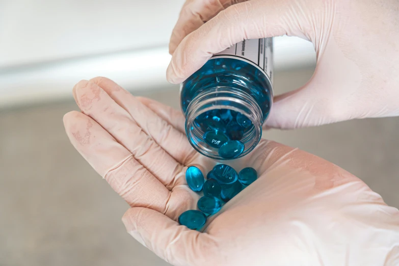 a close up of a person holding a jar of pills, phthalo blue, monochromatic teal, thumbnail, synthetic materials