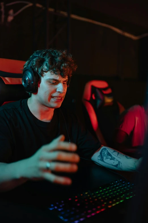 a man sitting in front of a computer with headphones on, an album cover, inspired by John Luke, pexels, renaissance, team ibuypower, intense expression, gaming room, medium shot of two characters