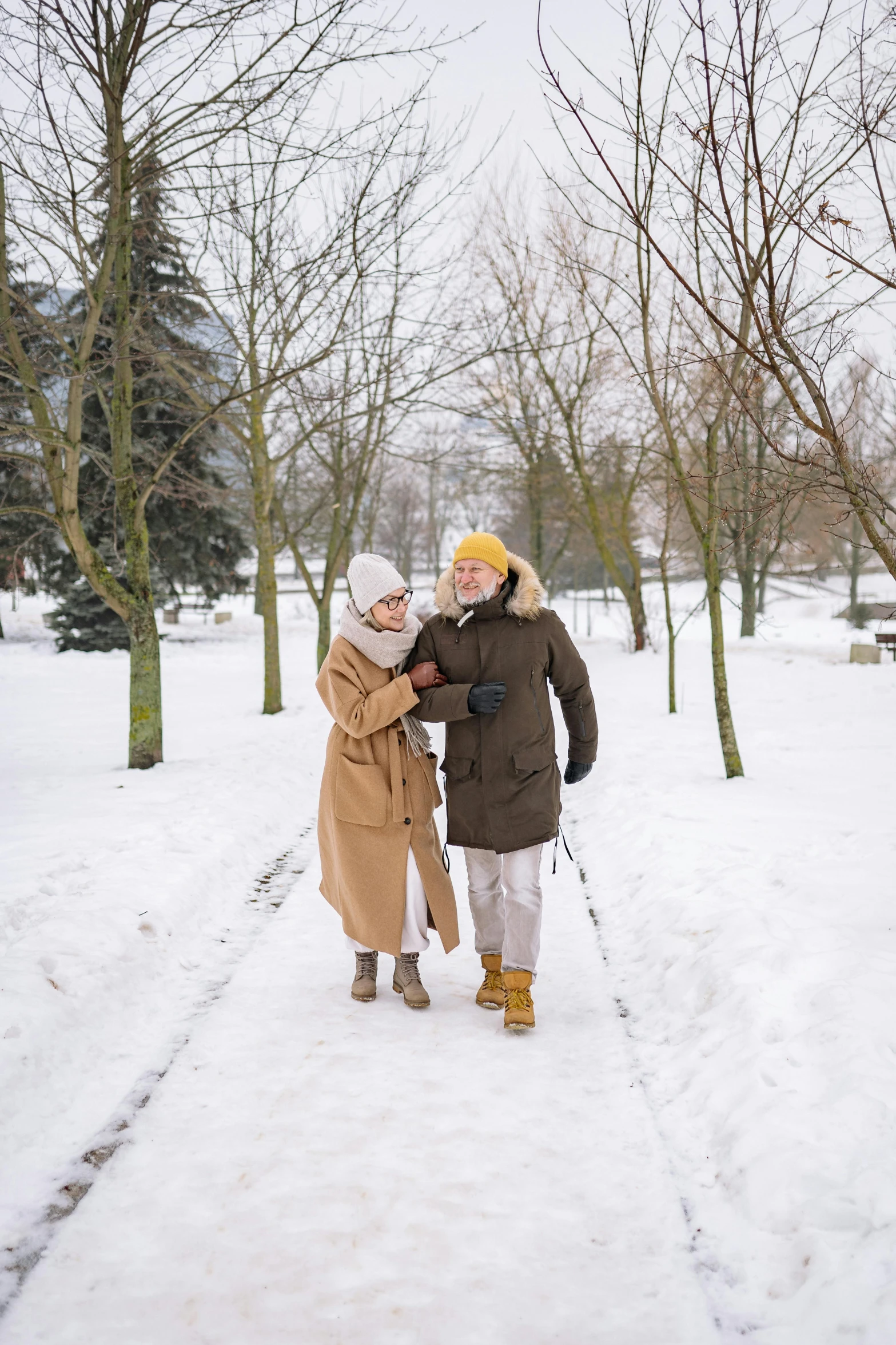 a man and a woman walking in the snow, taken in 2022, older woman, tan, gold