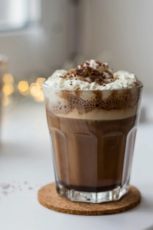 a close up of a cup of coffee on a table, profile image, whipped cream on top, sprinkles, fully chocolate