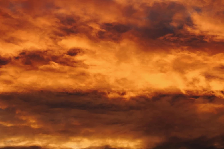 a plane flying through a cloudy sky at sunset, an album cover, inspired by Frederic Church, pexels contest winner, romanticism, dark oranges reds and yellows, dark mammatus cloud, brown, a close-up