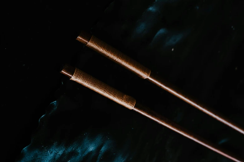 a pair of chopsticks sitting on top of a table, copper pipers, ripples, high quality product image”, dark. no text