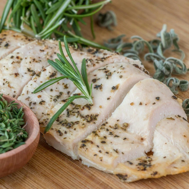 a piece of chicken sitting on top of a wooden cutting board, dried herbs, 6 pack, full-size, marquis cut