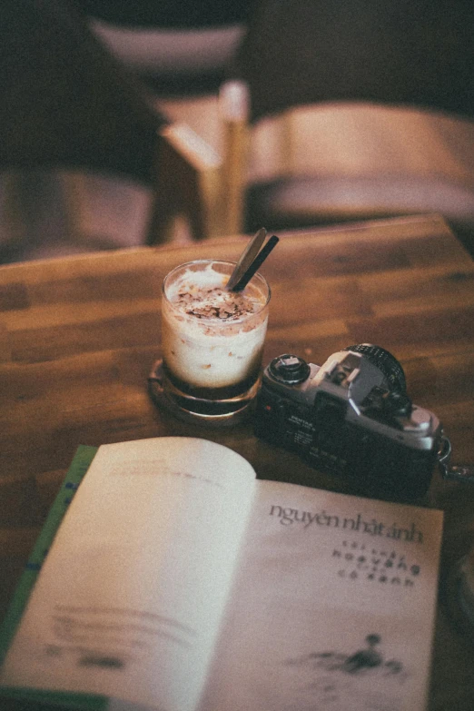 an open book sitting on top of a wooden table, drink milkshakes together, thawan duchanee, lomography photo, gif