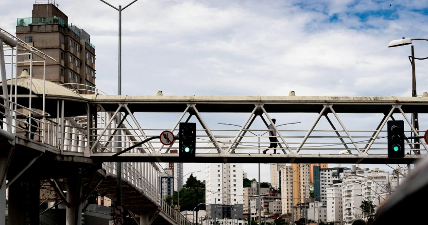 a man walking across a bridge over a street, by Joze Ciuha, in sao paulo, technical, intersection, holding close