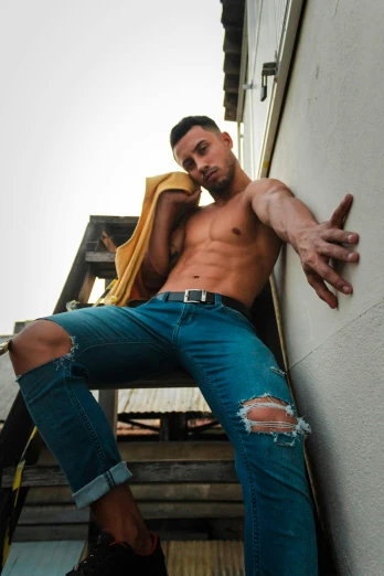 a shirtless man leaning against a wall, by Adam Dario Keel, instagram, blue jeans, cut out, glam photo, brightly colored