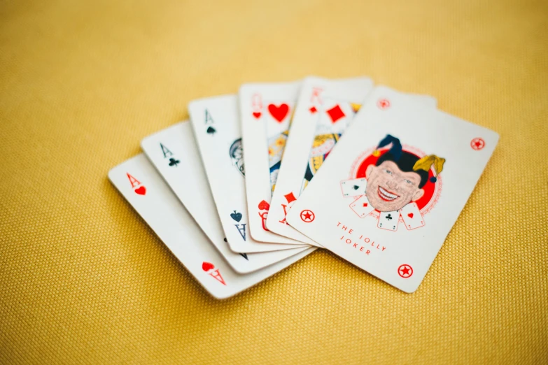 a bunch of playing cards sitting on top of a table, scarlet and yellow scheme, on a pale background, let's play, andy catling