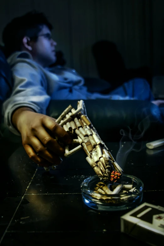 a person sitting on a couch playing a video game, an album cover, inspired by Elsa Bleda, pexels contest winner, skeletons smoking cigars, hand on table, at night time, teenage boy