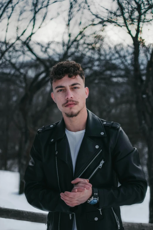 a man standing next to a fence in the snow, an album cover, by Cosmo Alexander, trending on pexels, she wears leather jacket, short stubble, asher duran, headshot profile picture