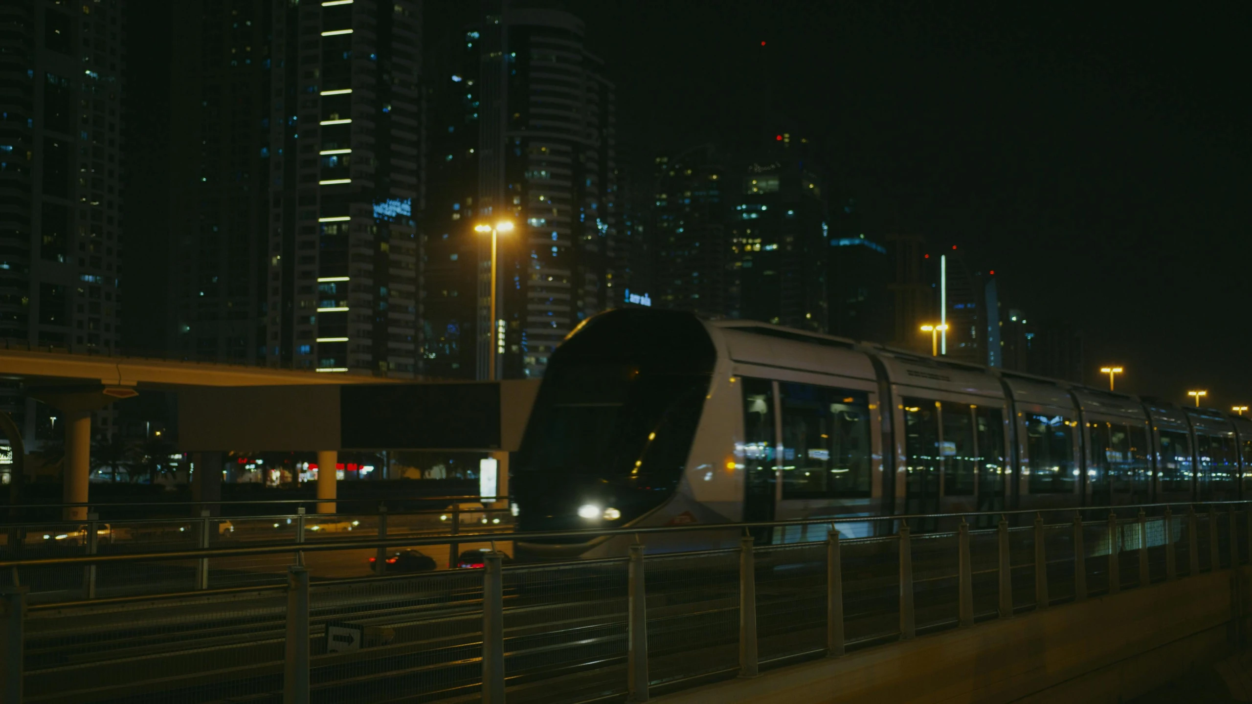 a train traveling through a city at night, dubai, fan favorite, cinematic luts, 8 k movie still