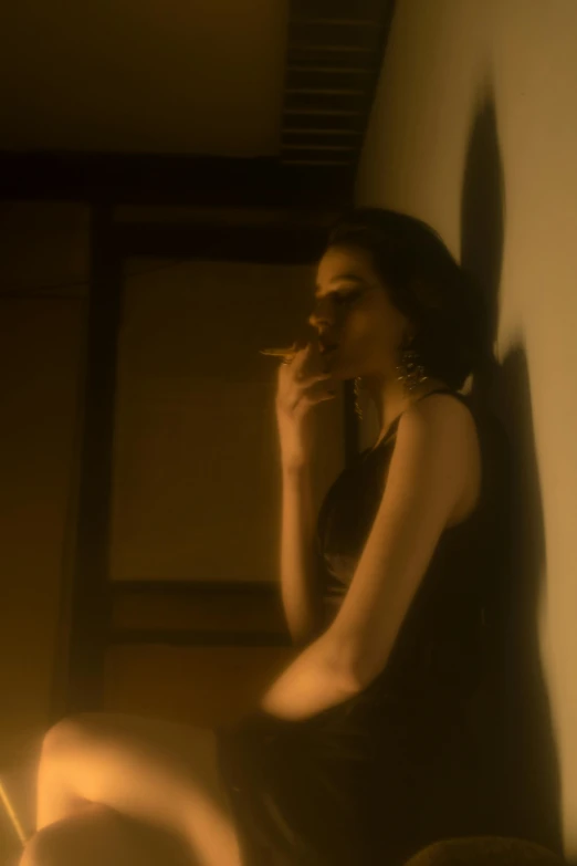 a woman sitting on a bed smoking a cigarette, inspired by Elsa Bleda, pexels contest winner, serial art, she is wearing a black dress, low quality footage, woman with black hair, standing in a dimly lit room