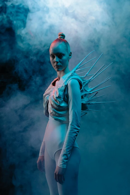 a woman in a white bodysuit with spikes on her head, inspired by Ignacy Witkiewicz, dramatic white and blue lighting, promotional image, wearable art, weta fx