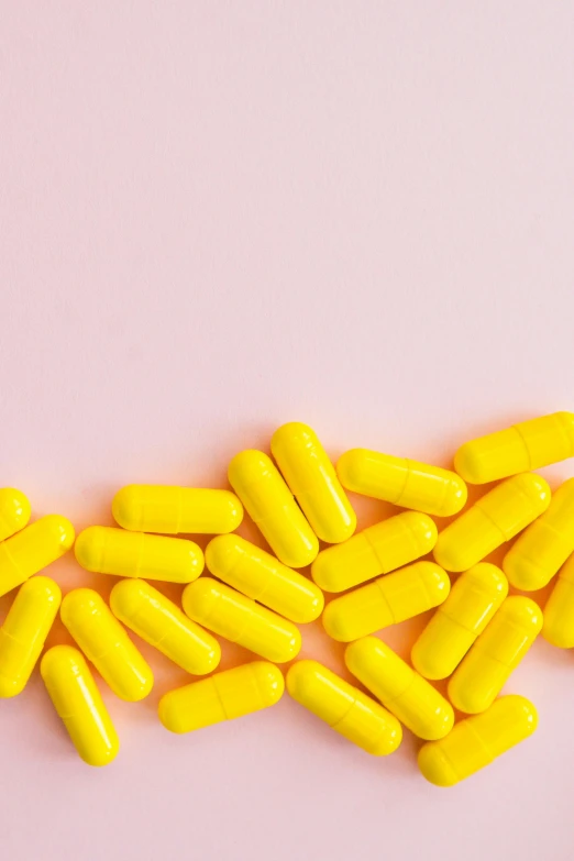 a pile of yellow pills on a pink background, by Nicolette Macnamara, antipodeans, tubes, on a white background, vibrant threads, multiple lights