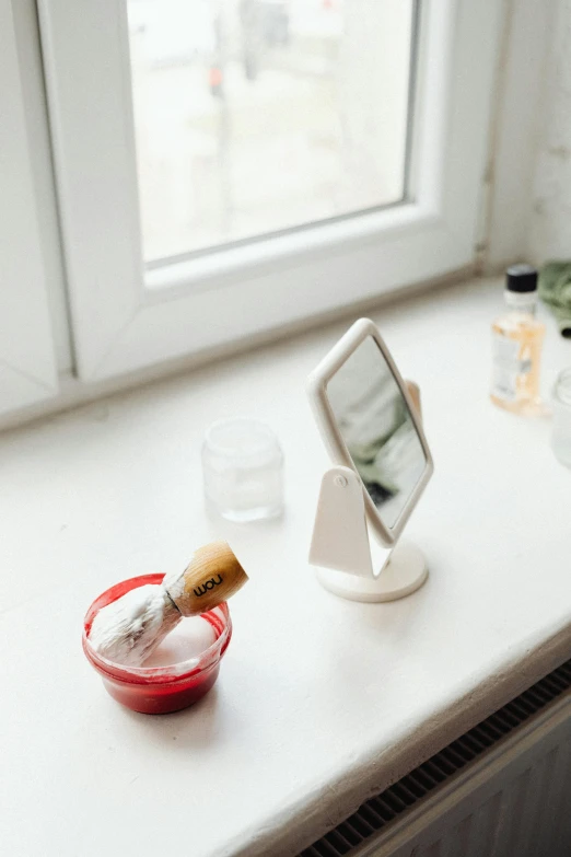 a cell phone sitting on top of a window sill, inspired by Louisa Matthíasdóttir, white powder makeup, doctors mirror, red and white, clean and organized