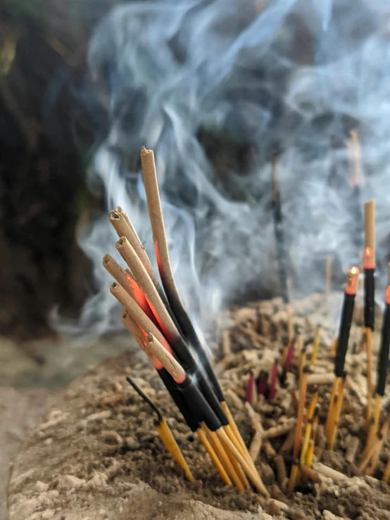 a bunch of sticks sticking out of the ground, unsplash, incense smoke fills the air, avatar image, close - up photograph, in an ancient altar