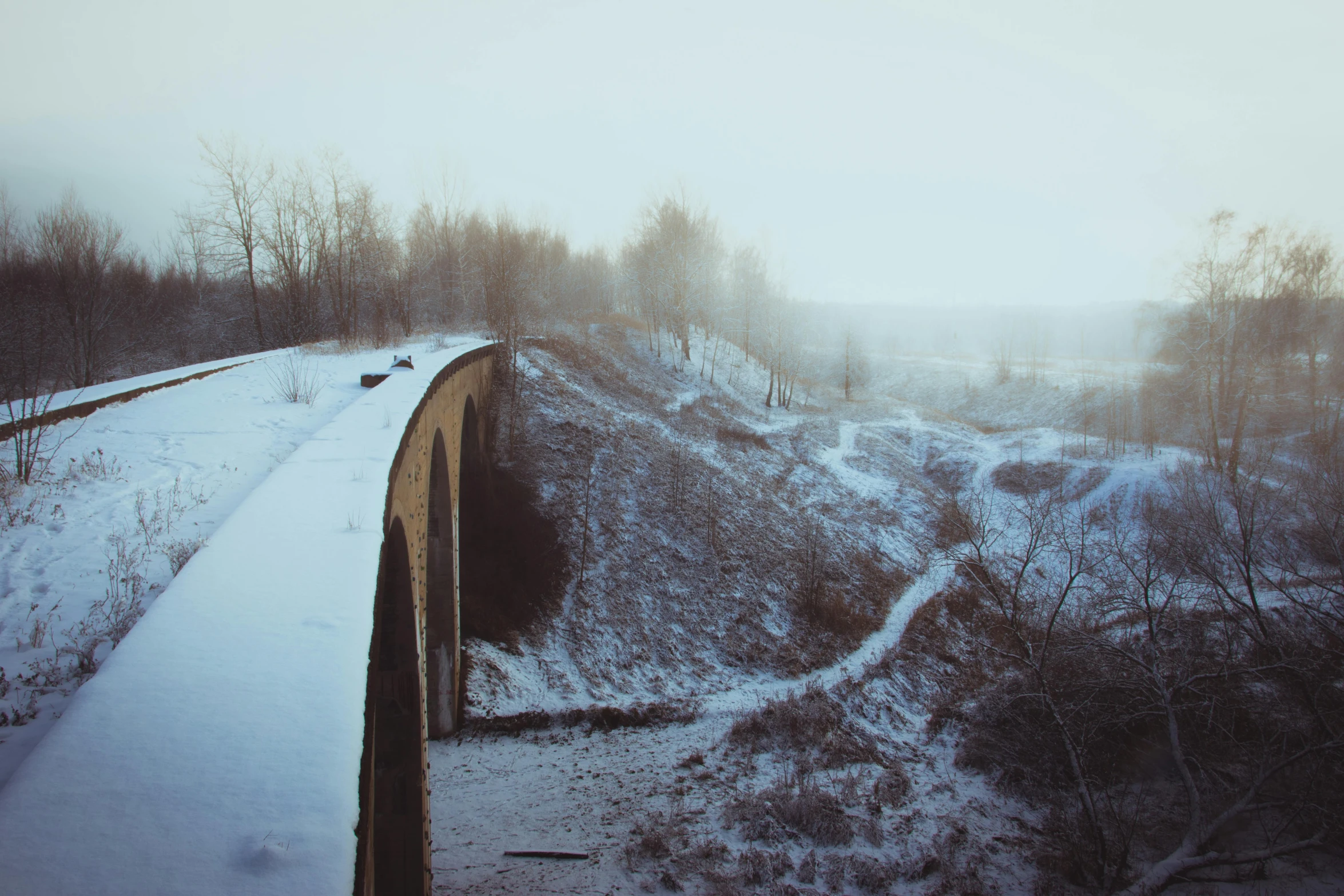 a train traveling over a snow covered bridge, pexels contest winner, romanticism, andrei tarkovsky scene, city wall, todd hido, aqueducts