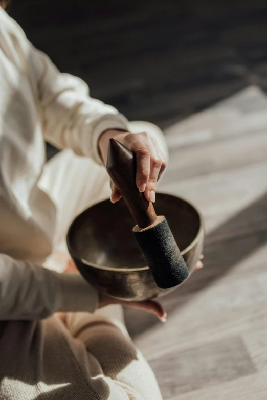 a woman sitting on the floor holding a singing bowl, pexels contest winner, renaissance, mortar and pestle, black, on a wooden tray, sleek hands