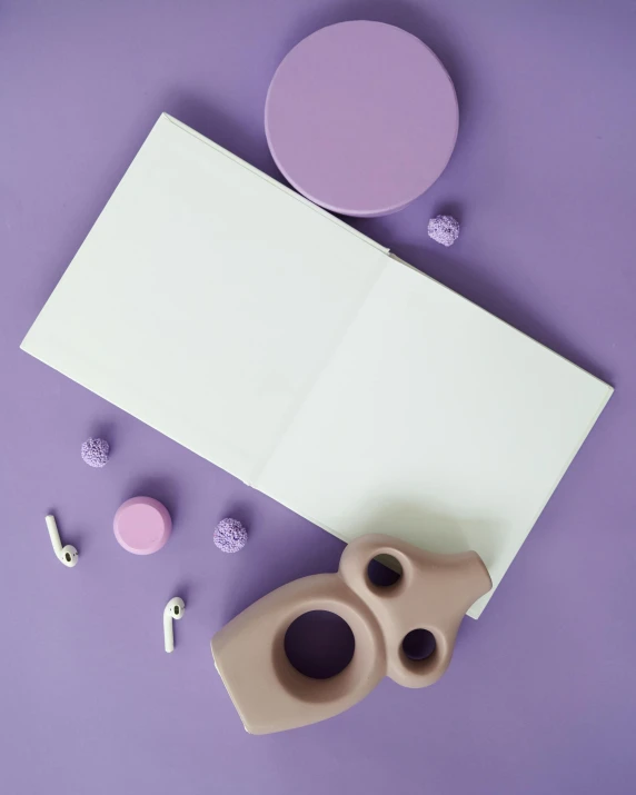an open book sitting on top of a purple surface, white ceramic shapes, toys, instagram picture, skincare