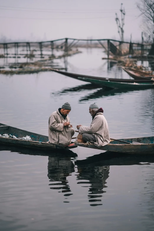 a couple of men sitting on top of a boat, by Ibrahim Kodra, pexels contest winner, winter setting, fishing town, asian man, calmly conversing 8k