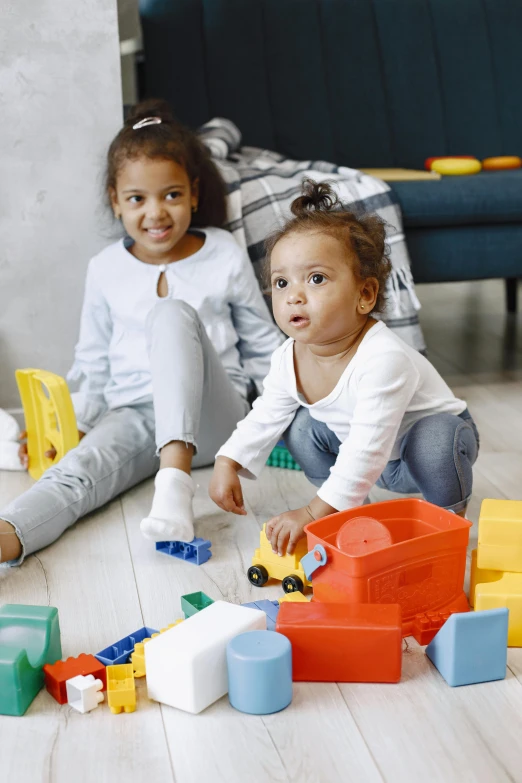 two children sitting on the floor playing with toys, promo photo, stacked image, multiple stories, confident