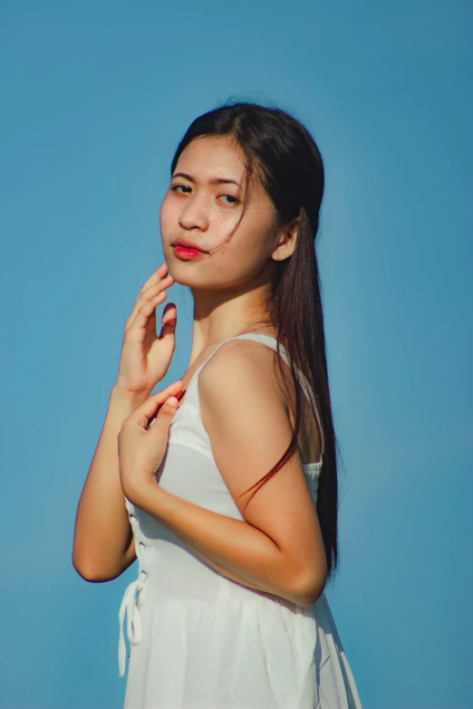 a woman in a white dress posing for a picture, inspired by Ren Hang, pexels contest winner, realism, blue background colour, wearing red tank top, young asian woman, sky blue