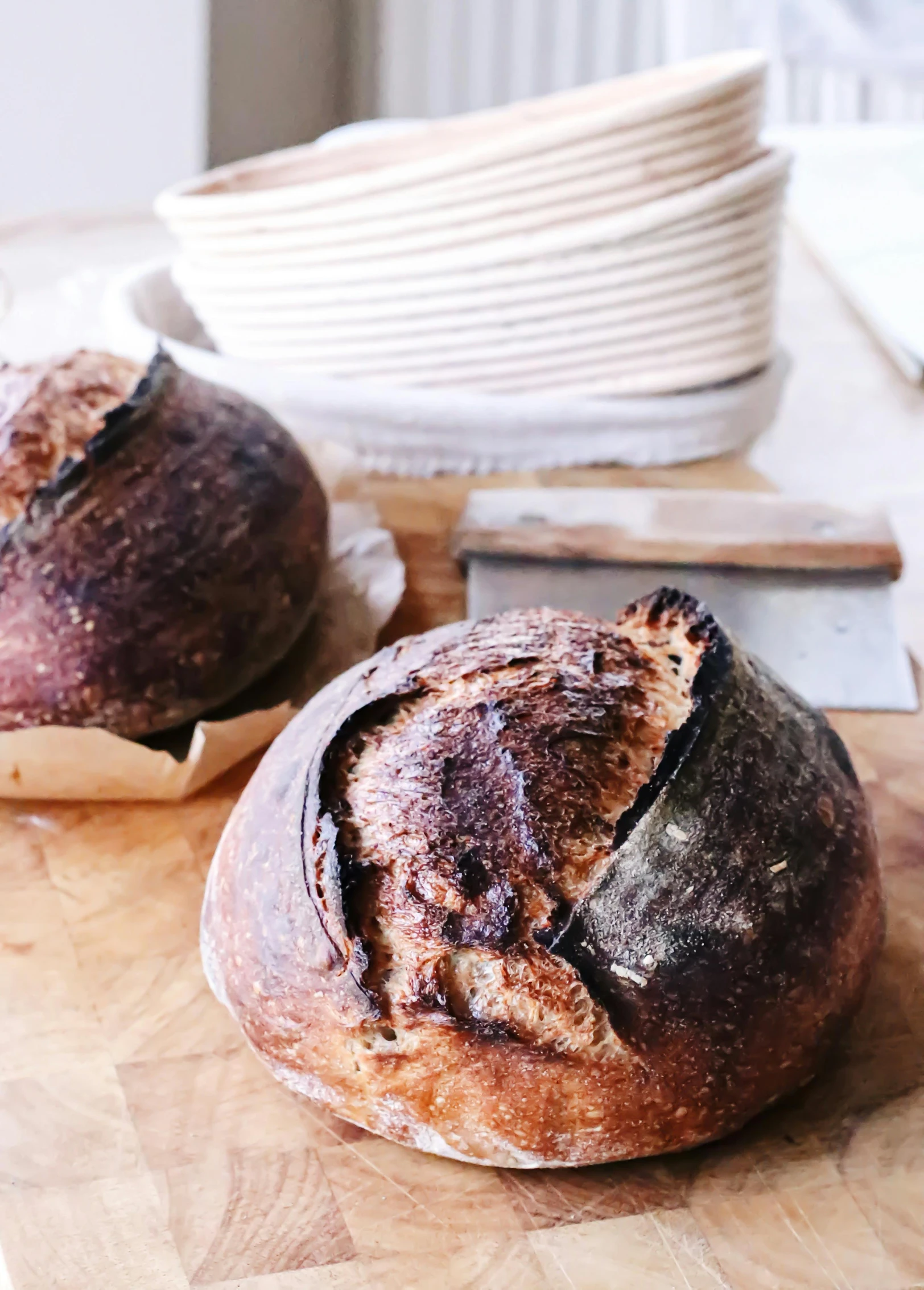 two loaves sitting on top of a wooden cutting board, a portrait, unsplash, award-winning crisp details”, very crispy, molten, malt