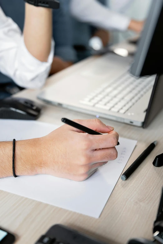 a person sitting at a desk writing on a piece of paper, a cartoon, trending on pexels, computers, black marker, sleek hands, non-binary