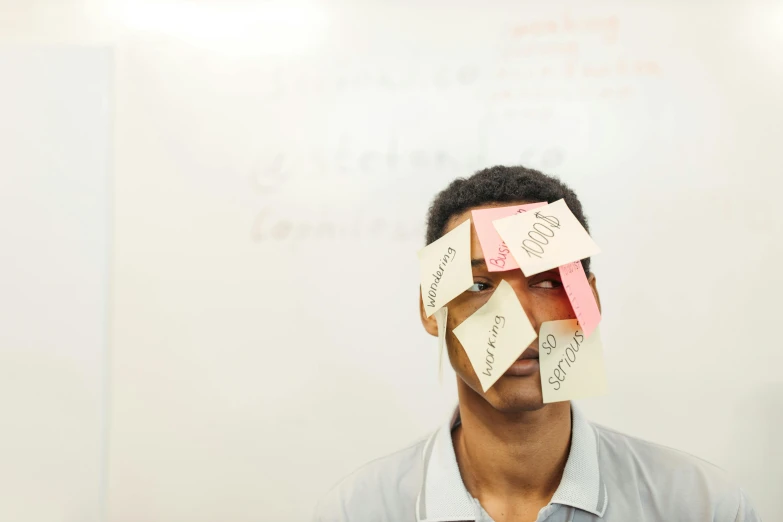 a man standing in front of a whiteboard covered in post it notes, an album cover, unsplash, academic art, markings on his face, background image, man is with black skin, in a school classroom