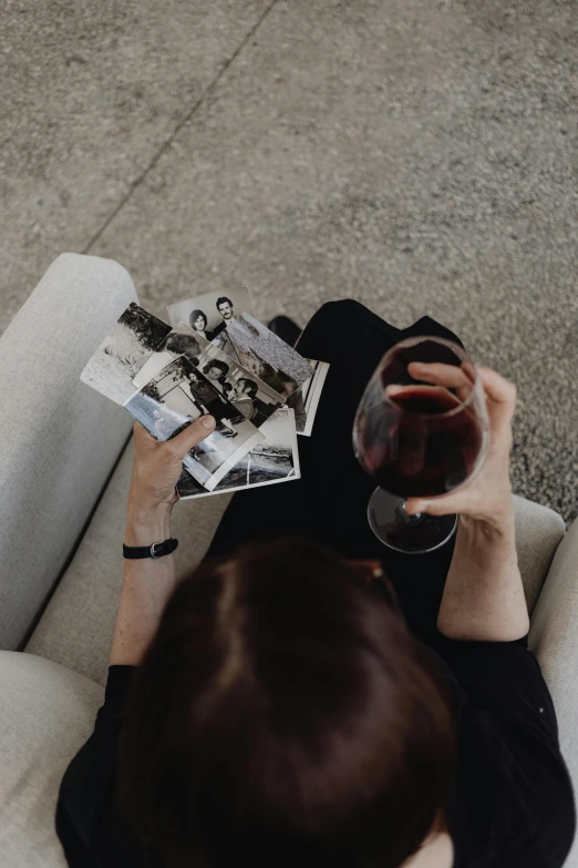 a woman sitting on a couch holding a glass of wine, a polaroid photo, inspired by Louis Stettner, pexels contest winner, profile image, wine label, flatlay, mid air shot