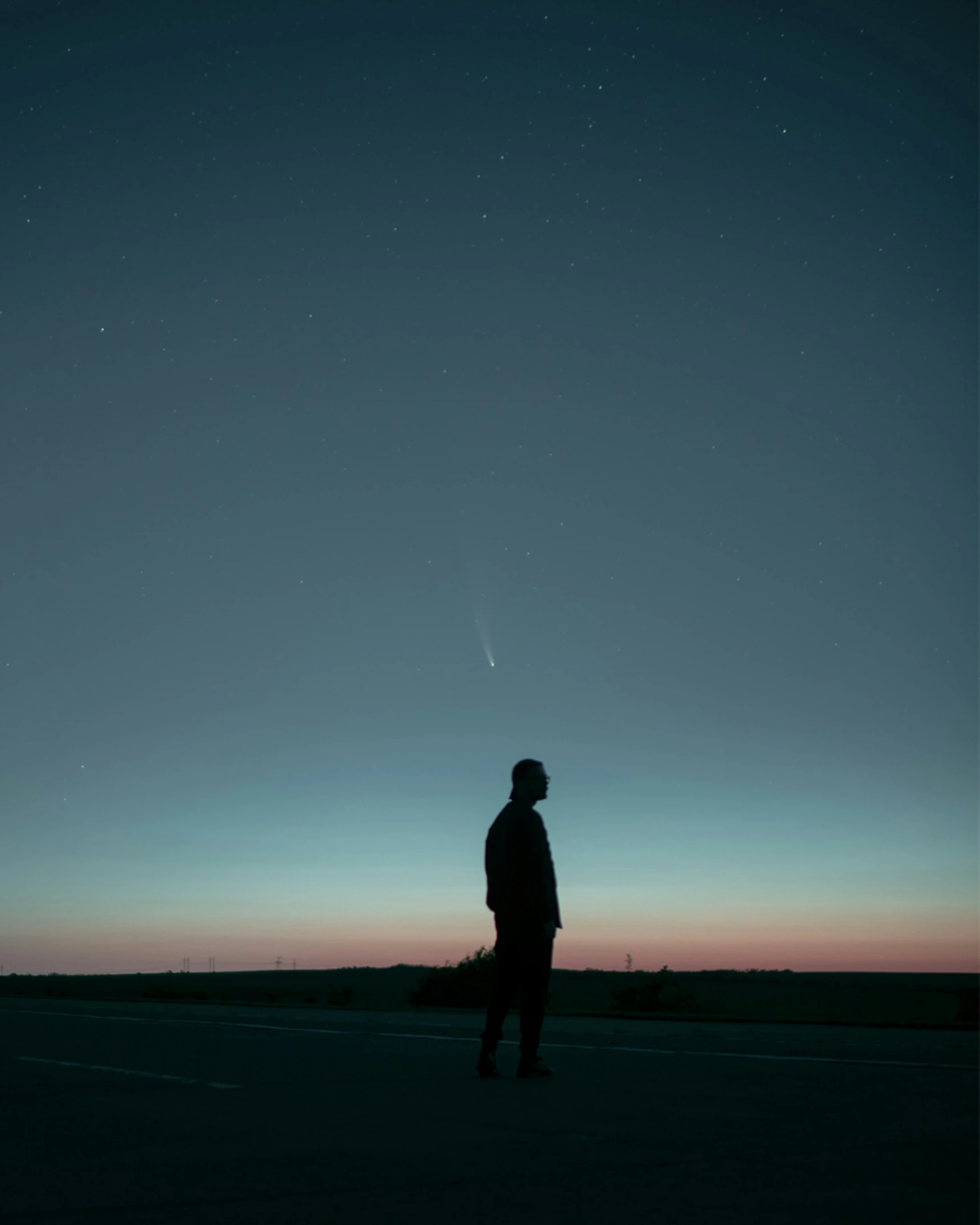 a person standing in the middle of a field at night, an album cover, pexels contest winner, postminimalism, comet, plain uniform sky, profile image, over his shoulder