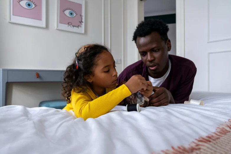 a man sitting on top of a bed next to a little girl, black man, playing board games, healthcare, instagram photo