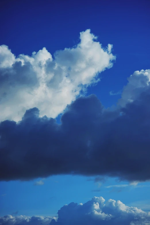 a plane flying through a cloudy blue sky, by David Donaldson, atmospheric clouds', brooding clouds', colour photograph, cloudless-crear-sky