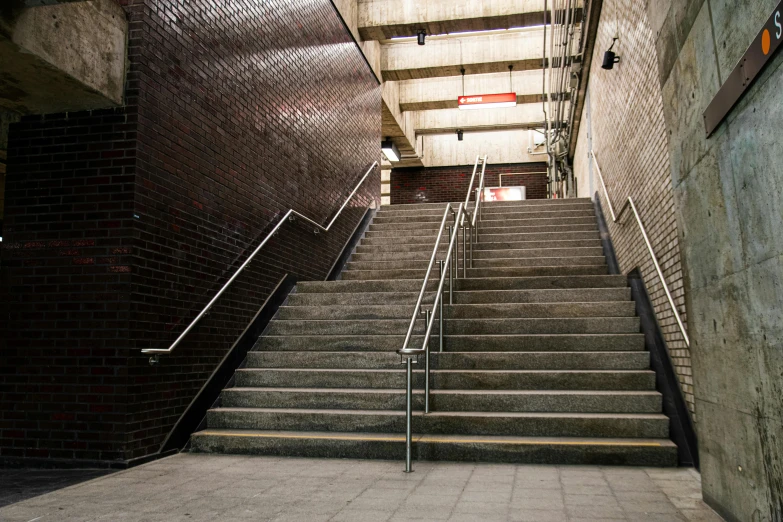 a man riding a skateboard down a flight of stairs, inspired by Thomas Struth, unsplash, brutalism, bus station, square, rossdtaws, ( ( railings ) )