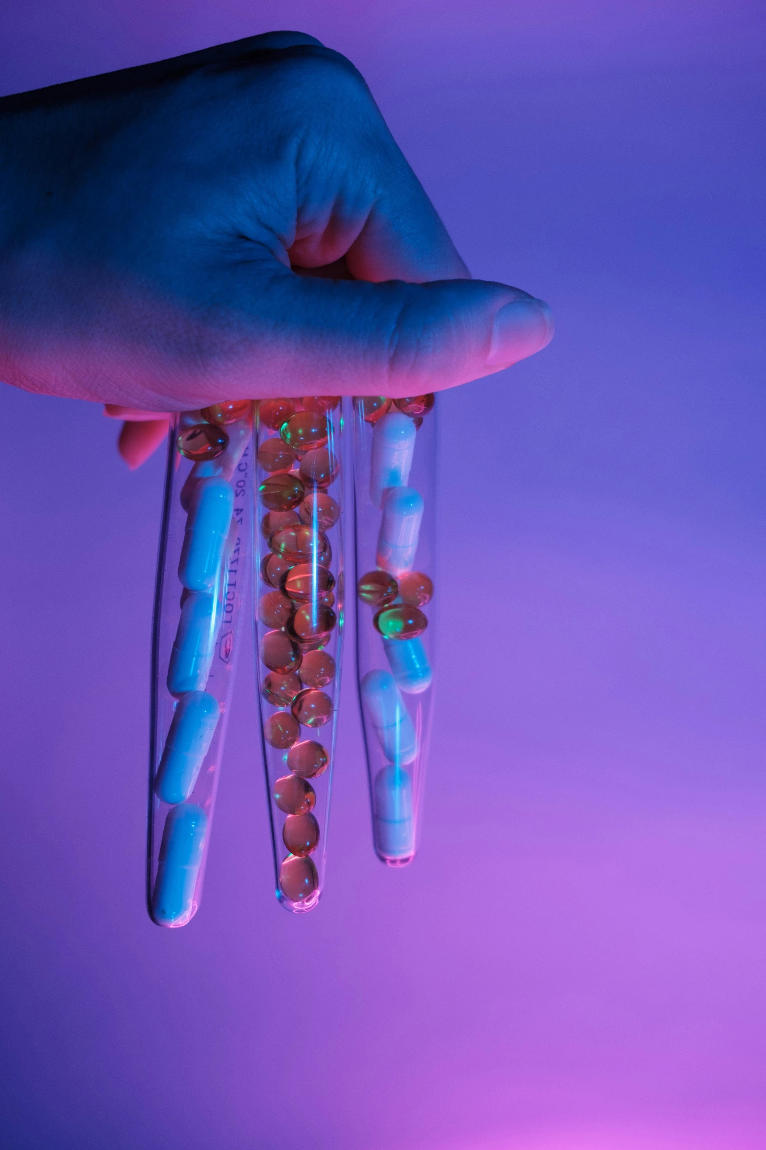 a person holding a bunch of beads in their hand, by Ryan Pancoast, conceptual art, pathology sample test tubes, blue and purle lighting, sculpted out of candy, hanging