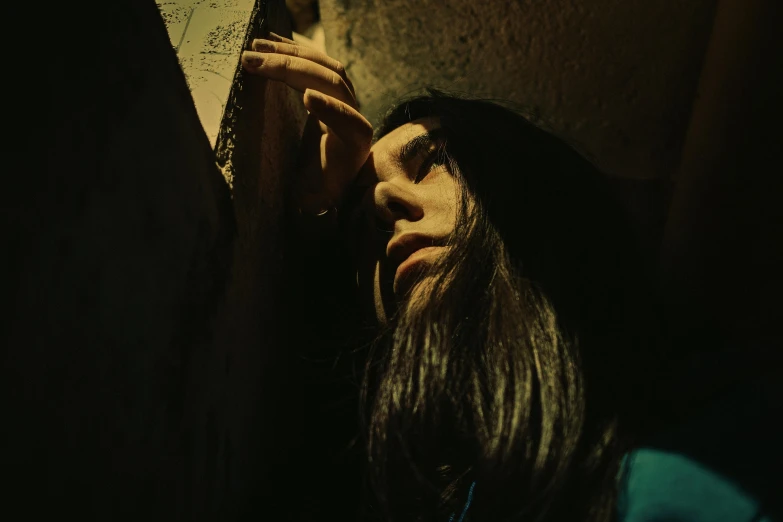 a woman leaning against a wall in a dark room, an album cover, by Elsa Bleda, pexels contest winner, conceptual art, with his long black hair, witch paying for her sins, in the style dora maar, movie still of a tired