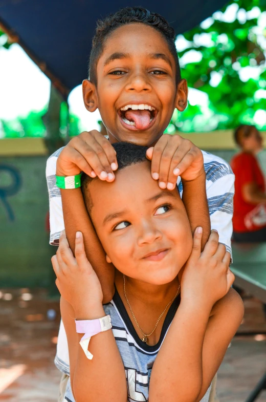 a couple of kids sitting on top of each other, by Emerson Silva, smiling into the camera, slide show, holding an epée, medium close up shot