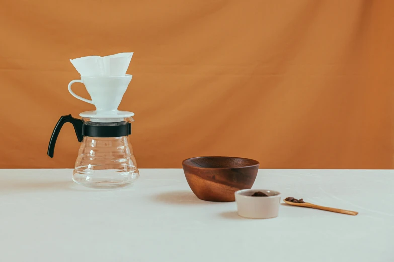 a coffee pot sitting on top of a table next to a wooden bowl, a still life, inspired by Miyagawa Chōshun, trending on unsplash, minimalism, background image, miniature product photo, various posed, cone shaped