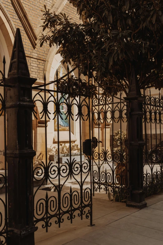 a wrought iron fence in front of a building, by Riad Beyrouti, pexels contest winner, romanesque, church interior, low quality photo, patio, late summer evening