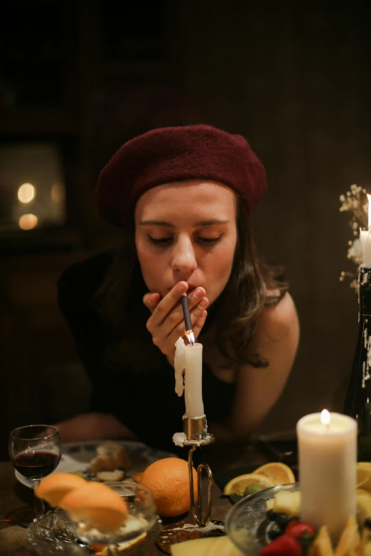 a woman sitting at a table blowing out a candle, inspired by Elsa Bleda, trending on pexels, renaissance, wearing a beret, fine dining, praying with tobacco, kissing