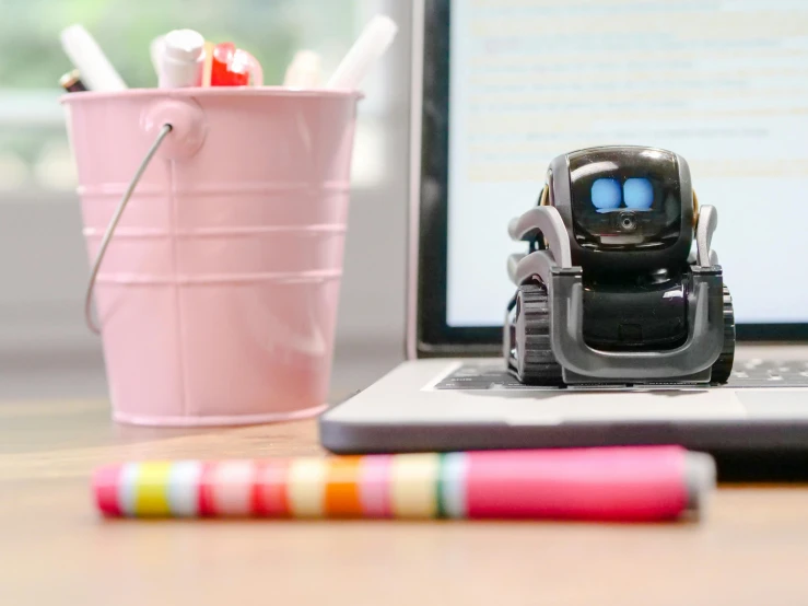 a toy robot sitting on top of a laptop computer, on a desk, square, alexa mini, black