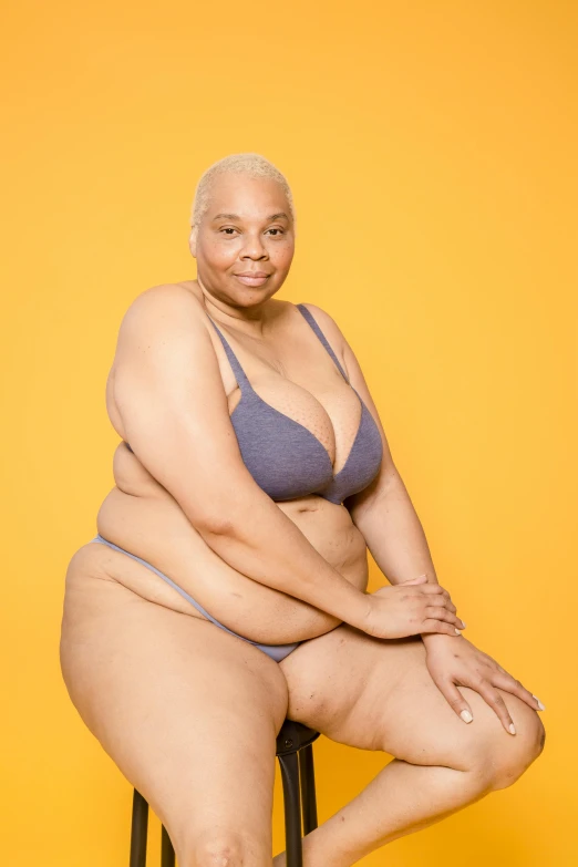 a woman in a bikini sitting on a stool, unsplash, fantastic realism, she has a jiggly fat round belly, portrait of ororo munroe, an epic non - binary model, posing together in bra