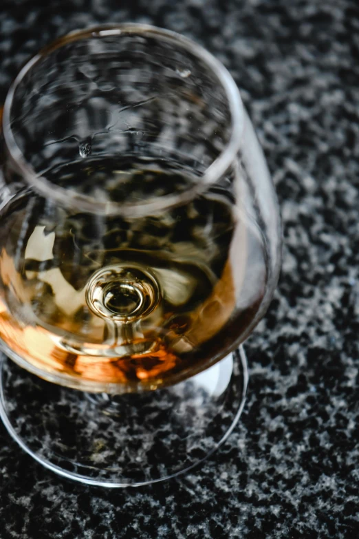 a glass of wine sitting on top of a table, by Adam Marczyński, pexels contest winner, renaissance, smooth marble surfaces, drinks bourbon, thumbnail, close - up on detailed