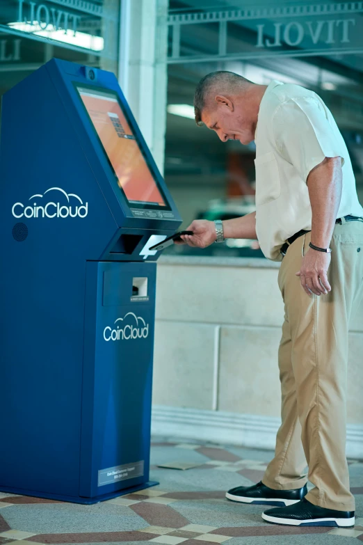 a man standing next to a blue machine, a digital rendering, unsplash, bitcoin, at checkout, cumulus, cornell