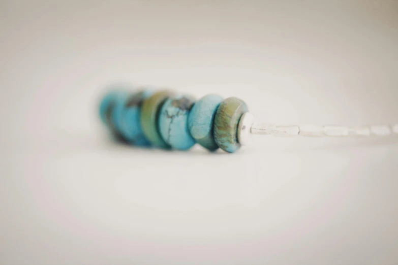 a couple of beads sitting on top of a table, a macro photograph, by Emma Andijewska, unsplash, hurufiyya, turquoise hair, surgical iv drip, stacked image, full body shot close up