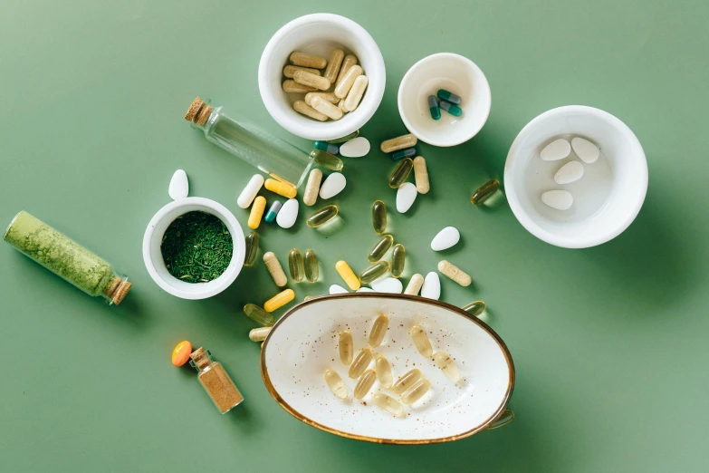 a bowl filled with pills sitting on top of a green table, a still life, by Julia Pishtar, trending on pexels, microorganisms, ingredients on the table, 🦩🪐🐞👩🏻🦳, petroleum vitamin