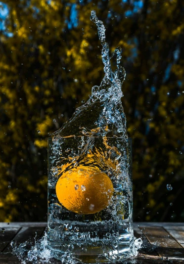 an orange being dropped into a glass of water, by Niko Henrichon, unsplash contest winner, still life photo of a backdrop, promo image, ice, lemon